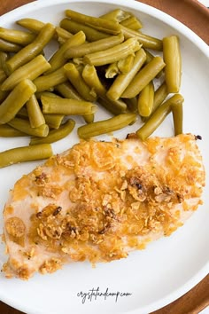 a white plate topped with green beans and chicken next to green beans on a wooden table