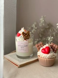 two cupcakes are sitting on top of an open book next to a candle