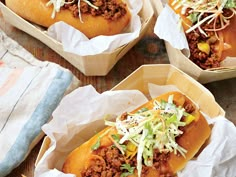 three chili dogs in paper containers with forks