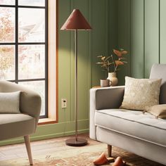 a living room filled with furniture and a lamp on top of a wooden floor next to a window