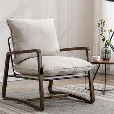 a chair with a pillow on top of it in front of a table and potted plant