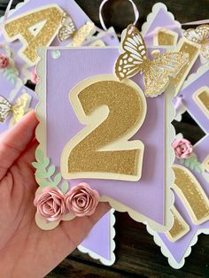 a hand holding up a purple and gold birthday card with the number two on it