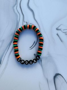 a beaded bracelet with black and orange beads on it's end, sitting on a white surface