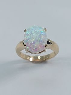 This stunning Lab Opal ring has been carefully crafted in 10k Yellow Gold, Synthetic Opal Stone . Great for any occasion! Buy it for your-self or for someone you love! This beautiful ring will not go unnoticed. All of my jewelry is handmade from scratch and of high quality.  Ring is size 6 1/2 but can be resized at no extra cost and will be shipped to you in an elegant gift box. A tracking shipping number will be provided to you once ring has been mailed. Ring Weight: 4.0 grams Stone Measurement Gold Opal Birthstone Ring For Anniversary, White Opal Birthstone Ring In 14k Gold, 14k Gold White Opal Birthstone Ring, Gold Opal Ring For Anniversary, Gold Opal Round Cut Ring For Anniversary, Gold Opal Ring For Anniversary With Round Cut, Gold Opal Ring Stamped 14k, Gold Opal Ring With Prong Setting As Gift, 14k Stamped Opal Promise Ring