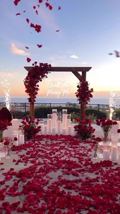 an outdoor wedding setup with red flowers and candles