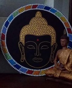 a buddha statue sitting on top of a wooden table next to a decorative wall hanging