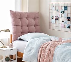 a bed with pink and blue comforters in a bedroom next to a white table