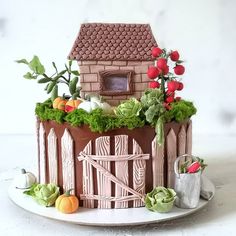 there is a cake that looks like a farm house with flowers and vegetables on it