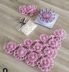 crochet flowers are being worked on with scissors and thread, along with other crafting supplies