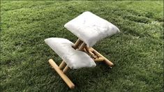 two white pillows sitting on top of a wooden chair in the middle of some grass