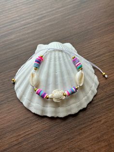 a white shell with colorful beads on a wooden table