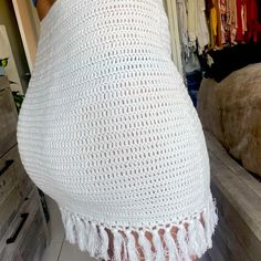 there is a white crochet shawl with tassels on the bottom