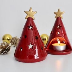 two small red christmas trees with gold stars on them and a lit candle in the middle