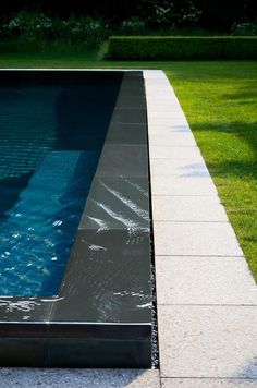 an empty swimming pool surrounded by green grass