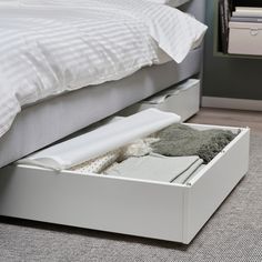 a bed with two drawers underneath it and a blanket on the floor next to it