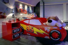 a red race car bed with a stuffed animal in it