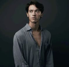 a young man is posing for a photo in front of a black background with his hands on his hips