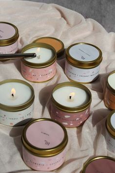 several candles are sitting on a table with pink and gold tins next to each other