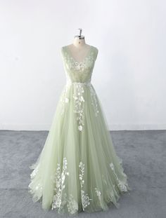 a light green dress with white flowers on the waist and back, sitting on a mannequin