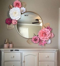 there is a mirror with flowers on the wall above it and a dresser in front of it