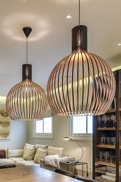 three wooden lamps hanging from the ceiling in a living room with couches and coffee table