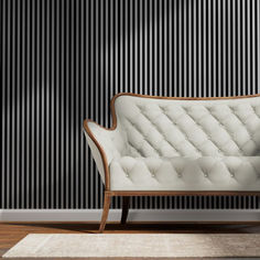 a white couch sitting on top of a wooden floor next to a black striped wall