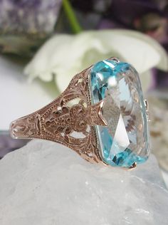 Simulated Aquamarine Rose Gold plated Sterling Silver Ring Treasure Design#D202 This is an Edwardian era reproduction filigree ring. The Art Deco design is beautifully created in rose gold plated solid sterling silver. This is a flawless man-made/simulated sky blue aquamarine that measures 18mm by 13mm. The ring is 3/4" (19mm) North to South on the finger. The inside of the band is etched 925 (sterling). Notice the intricate and detailed floral design. The rose gold 'embraced' silver filigree ac Heirloom Rose Gold Topaz Gemstone Ring, Elegant Oval Rose Gold Topaz Ring, Elegant Rose Gold Oval Topaz Ring, Ornate Rose Gold Jewelry With Intricate Design, Vintage Rose Gold Jewelry With Intricate Design, Ornate Rose Gold Filigree Jewelry, Classic Rose Gold Topaz Ring For Formal Events, Classic Rose Gold Topaz Ring For Formal Occasions, Victorian Rose Gold Engraved Ring