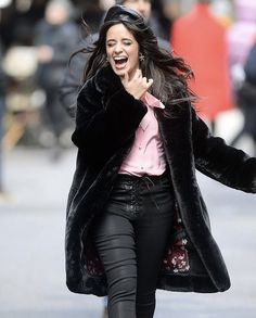 a woman is walking down the street talking on her cell phone while wearing black pants and a pink shirt