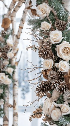 white flowers and pine cones are hanging from the branches in this winter wedding ceremony arch