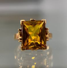 Gorgeous emerald cut synthetic yellow stone statement ring set in yellow gold.  Pre-loved item  Stamped 10KT (key symbol) LORIE Ring Size (approx.): 6 US Weight: 5.31 US **FREE shipping within Canada and USA** If you have any questions or concerns, please do not hesitate to contact us. We will be more than happy to help you and answer any inquiries.  We invite you to check out our shop for more fabulous items! Fine Jewelry Yellow Rings With 17 Jewels, Formal Gold Jewelry With Rectangular Stone, Gold Jewelry With Rectangular Stone For Formal Events, Gold Jewelry With Rectangular Stone For Formal Occasions, Gold Jewelry With Rectangular Accent Stones, Emerald Cut Citrine Rings, Rectangular Gold Jewelry With Accent Stones, Formal Gold Jewelry With Accent Stones, Gold Jewelry With Accent Stones For Formal Occasions