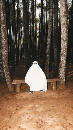 a covered bench in the middle of a forest with trees around it and one person sitting on top