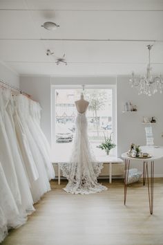 a bridal gown is displayed in front of a window at a wedding dress shop