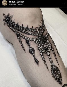 a black and white photo of a woman's leg with an intricate tattoo design on it