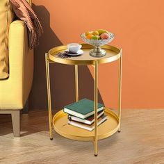 a table with books and a bowl of fruit on it next to a yellow chair