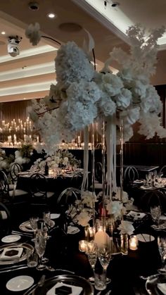 an elegant centerpiece with white flowers and candles is displayed in the middle of a dining room