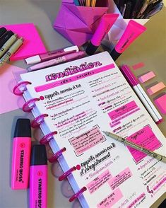 a pink notebook with writing on it next to some pens and other items that include markers