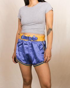 Embrace a piece of athletic history with these vintage 50s/60s basketball shorts from Gold Band. Featuring a stunning blue color with yellow trim detail, these shorts come with a buckle waistband with adjustable holes, giving them a unique and classic look. They feel like a soft rayon blend. Features: Beautiful blue color with yellow trim detail Buckle waistband with adjustable holes Feels like a rayon blend Brand: Gold Band Size: Best fits Small-Medium, for someone with a 26-27" waist Measurements: Waist 27"-28.5" Rise 12.75" Hips 40" Inseam 2.5" Fit Notes: The waistband no longer stretches, and the fabric has no stretch, making them best suited for someone with a small waist-to-hip ratio. The model has a 25" waist and 35" hips, and the shorts were slightly big on her. Condition: The elas Retro Blue Athletic Shorts, Retro Athletic Shorts For Sports, Vintage Blue Sports Shorts, Basketball Vintage, Vintage Basketball, Outfits Mit Shorts, Yellow Trim, Basketball Shorts, Trim Detail