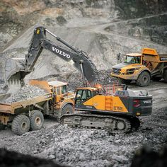 two dump trucks are dumping gravel into a pile