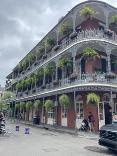 a black car parked in front of a tall building with flowers on the balconies