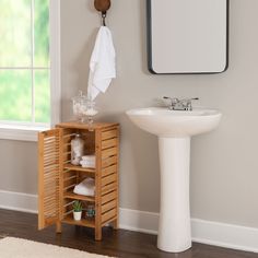 a white sink sitting next to a wooden cabinet under a mirror on top of a wall