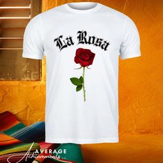 Vintage Rose Tee, La Rosa Shirt, Gothic Rose Top, Old English Style, Elegant Florals, Retro Rose Print, Classic Rose Tee, Floral Script Art, La Rosa Apparel, Romantic Blooms, Vintage Typography, Old World Charm, Rose Garden Wear The unisex heavy cotton tee is the basic staple of any wardrobe. It is the foundation upon which casual fashion grows. All it needs is a personalized design to elevate things to profitability. The specially spun fibers provide a smooth surface for premium printing vividi White Cotton T-shirt With Rose Print, Pink Rose Print Crew Neck T-shirt, Cotton Crew Neck Top With Rose Print, White Rose Print Short Sleeve Top, Casual Rose Tops With Rose Design, Rose Color Crew Neck Top With Rose Print, Mexican Tshirt, Garden Wear, Old English Style