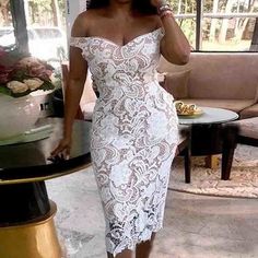 a woman in a white lace dress is talking on her cell phone while standing next to a table