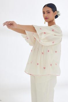 Cream handwoven jamdani cotton top with heart pattern, raglan sleeves, front tasselled tie-up and stitch details on hem.
Component: 1
Pattern: Handwoven and Hand Stitched
Type Of Work: Heart Pattern and Running Stitch Details
Neckline: Round
Sleeve Type: Raglan Sleeves
Fabric: Handwoven Jamdani Cotton
Color: Cream
Other Details: 
Attached lining
Note: The pants and inner top worn by the model is not for sale
Occasion: Work,Party,Resort - Aza Fashions White Cotton Top With Back Tassel Tie-up, Cotton Short Sleeve Blouse With Tassels, Cotton Blouse With Tassels And Short Sleeves, Short Sleeve Cotton Blouse With Tassels, White Cotton Tops With Back Tassel Tie-up, White Blouse With Back Tassel Tie-up, Traditional Cotton Blouse With Tassels, Cotton Blouse With Back Tassel Tie-up, Long Sleeve Cotton Blouse With Back Tassel Tie-up