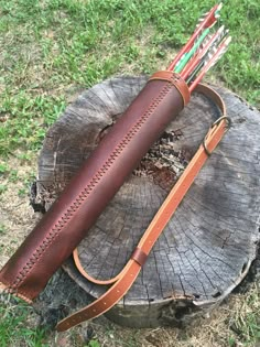 a leather case with arrows in it sitting on top of a tree stump next to a knife