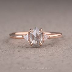 a rose cut diamond ring with two pear shaped diamonds on the band, set in 18k gold