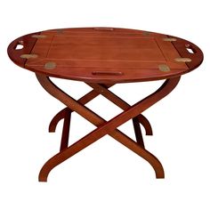 an oval wooden table with two crossed legs and leather tray on one end, in the shape of a cross