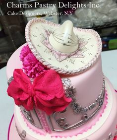 a pink and white cake with a hat on top