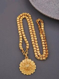 a gold necklace with a flower on it and a chain attached to the clasps