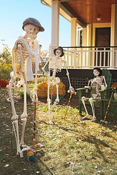 three skeletons sitting in front of a house