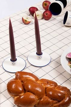 a table topped with lots of food on top of a white tiled counter next to two candles